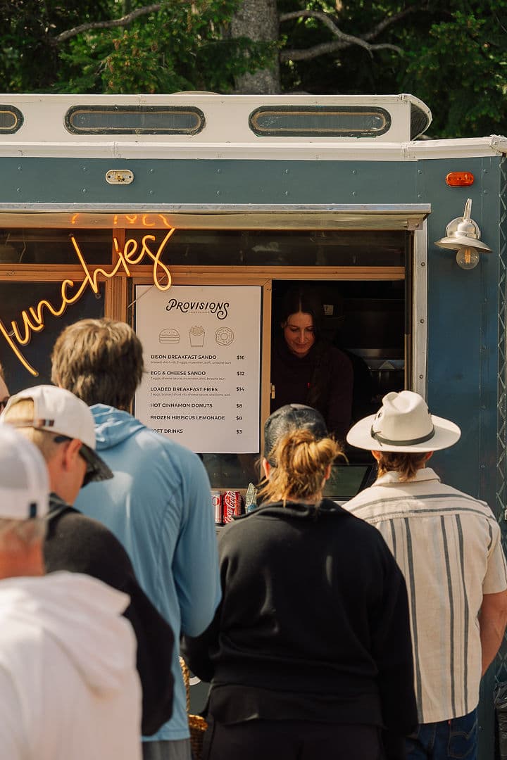 Customers lined up at the Provisions food truck reading the breakfast menu board