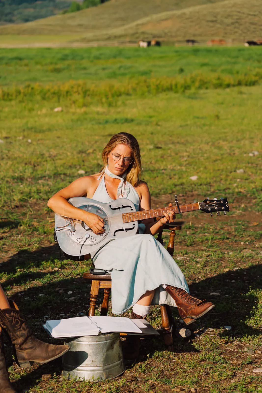 A musician playing guitar in the field at golden hour