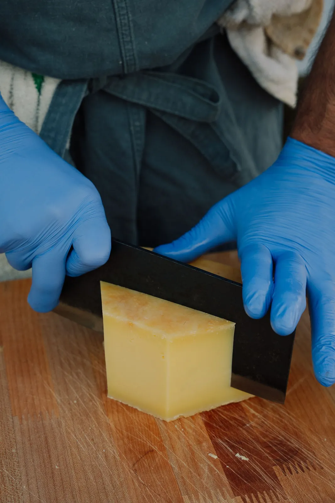 A chef slicing a block of cheese during prep