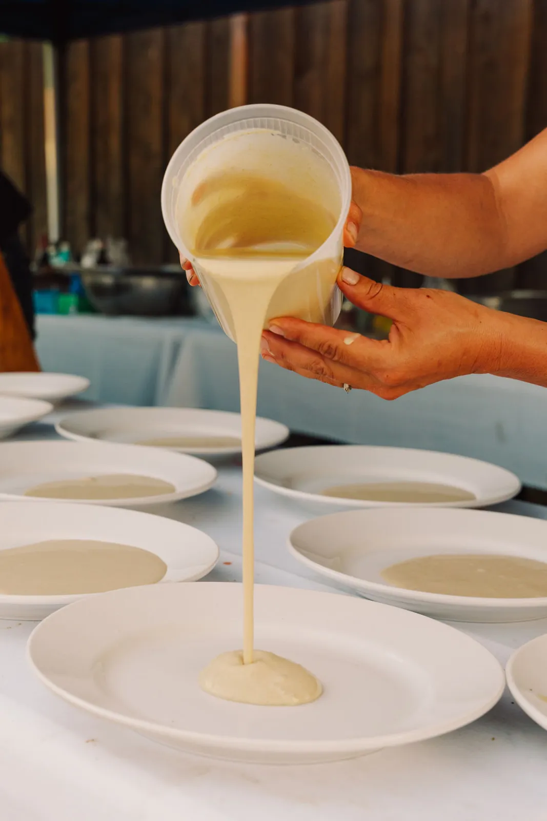 A chef pouring soup into plates along the dinner table