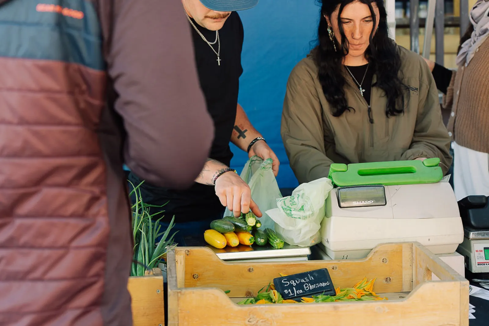 A vendor bagging fresh greens and vegetables for a shopper