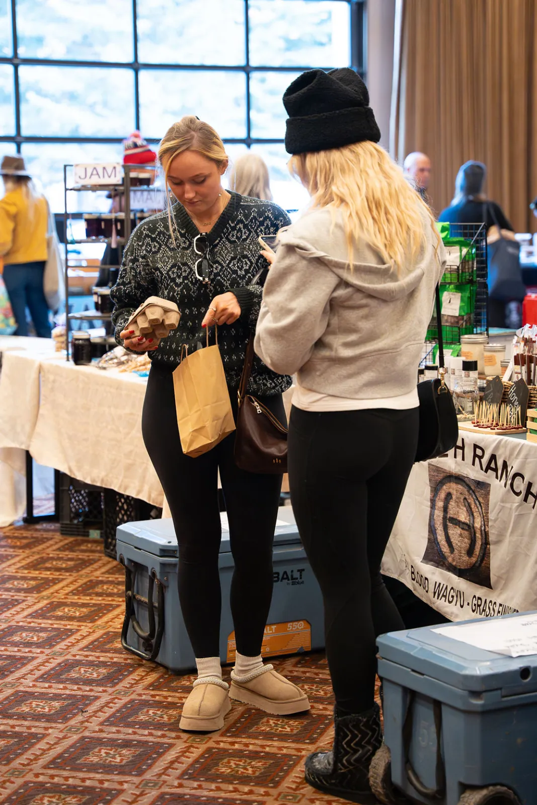 Two shoppers browsing a booth at the winter market